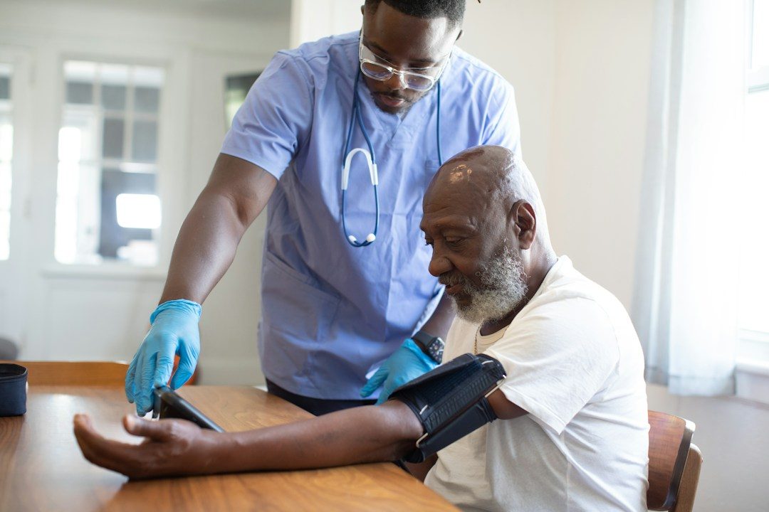 Nurse checking an older man's blood pressure at home